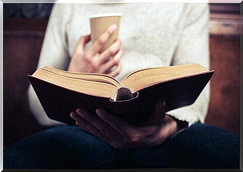 Person with coffee cup reading self-help books