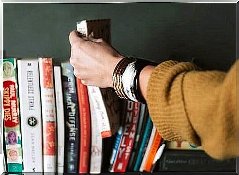 A hand selects a book from a shelf