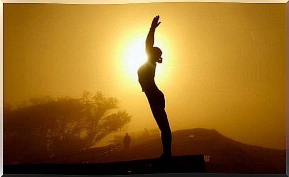 Woman practices tai chi in front of sun