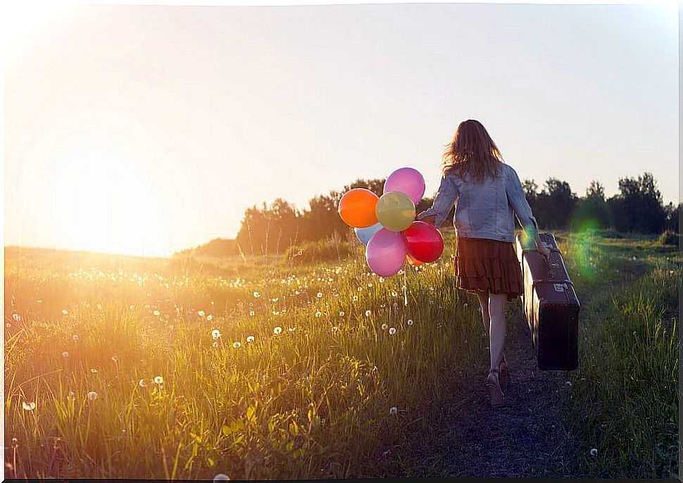 Girl carrying suitcase and balloons