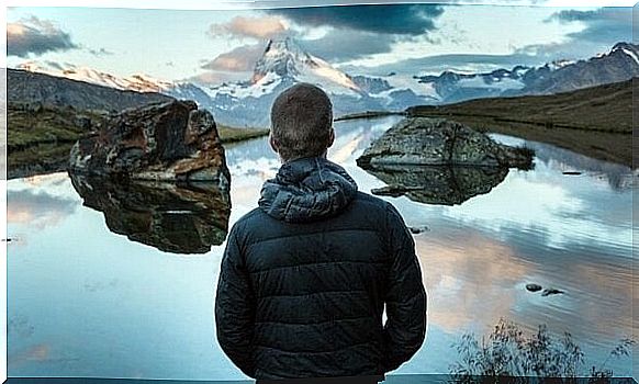 Man in front of lake explores the world to become emotionally stronger