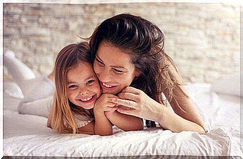 A mother hugs her daughter in bed