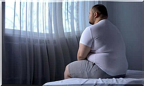 Overweight man sitting on bed