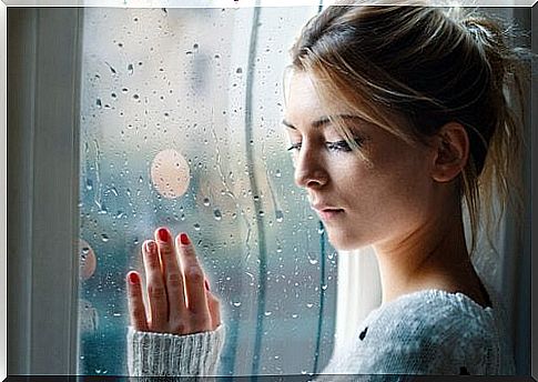 A woman with negative emotions standing by window