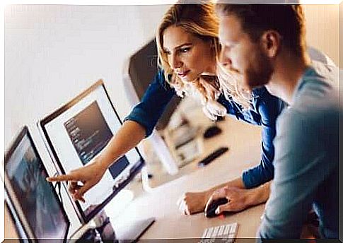 Man and woman at multiple computer screens