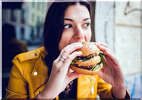 Woman eating a burger, symbolizing habits that lower your iq