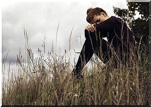 Woman on field resting head on knees