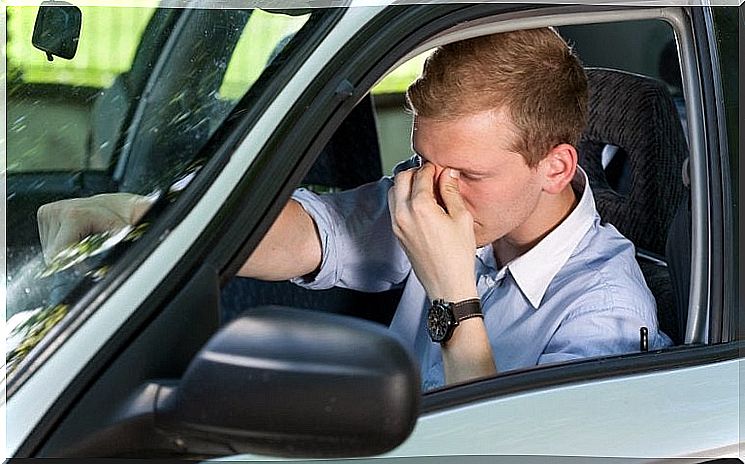 man taking care of his forehead by car