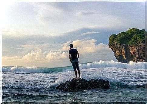 Guy standing on rocks and looking at the sea