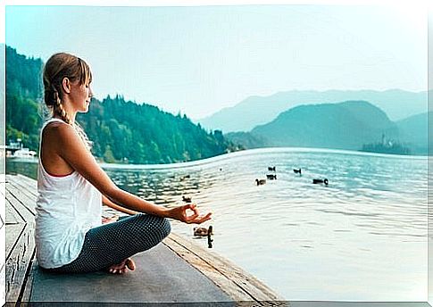 Woman practicing yoga by lake