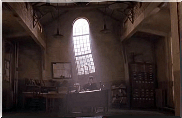 A man sitting at a desk in a dark room in a prison