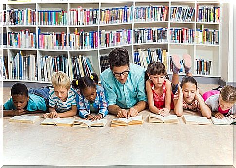 Children read book on floor with good teacher