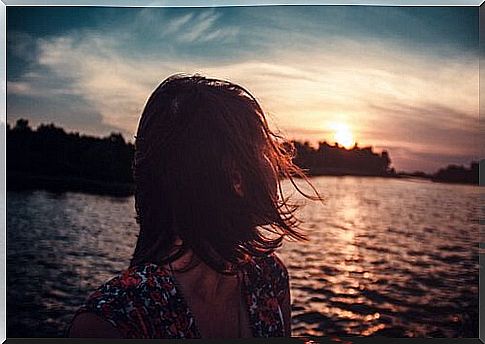 A woman watching the sunrise by the sea